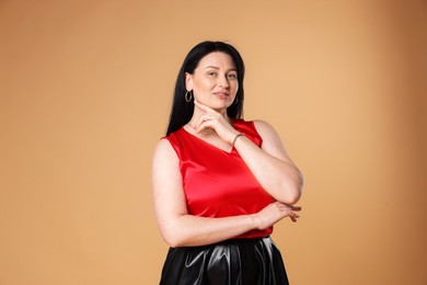 Photo of Portrait of smiling plus size model on beige background. Overweight