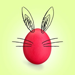 Image of Red Easter egg with bunny ears and whiskers on light green background