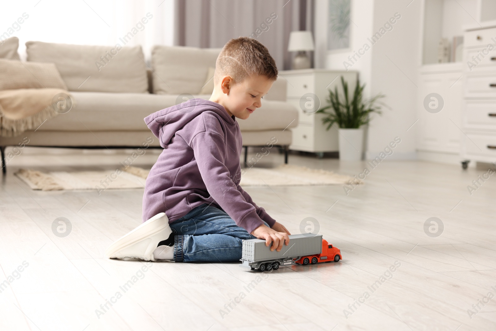 Photo of Little boy playing with toy car at home