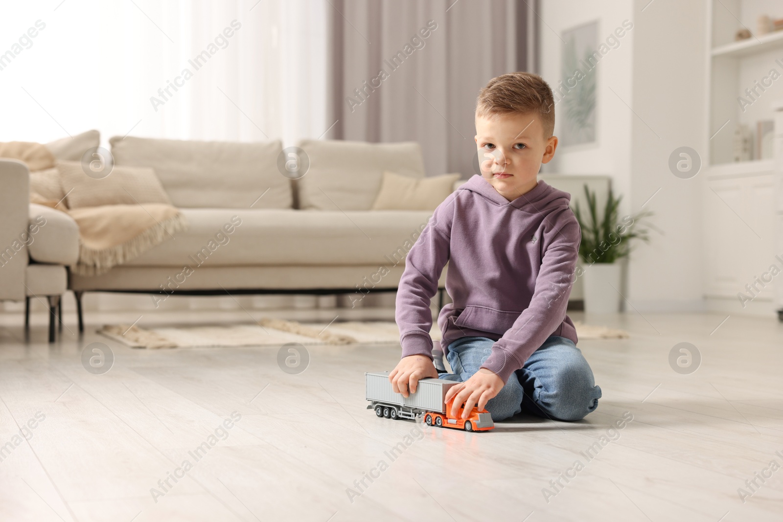 Photo of Little boy playing with toy car at home. Space for text