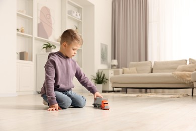 Photo of Little boy playing with toy car at home. Space for text