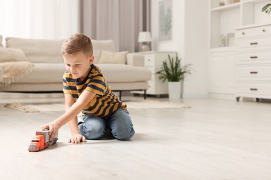 Photo of Little boy playing with toy car at home. Space for text