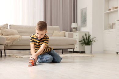 Photo of Little boy playing with toy car at home. Space for text