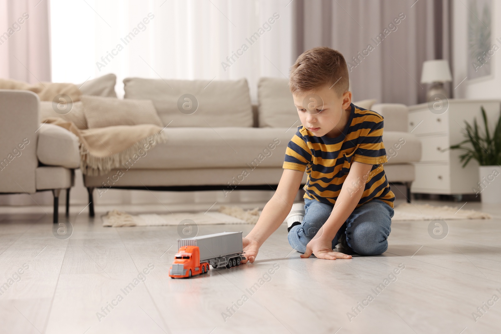 Photo of Little boy playing with toy car at home. Space for text