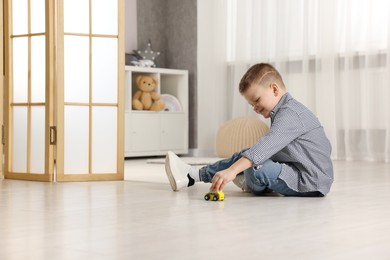 Little boy playing with toy car at home. Space for text