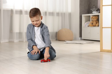 Little boy playing with toy car at home. Space for text