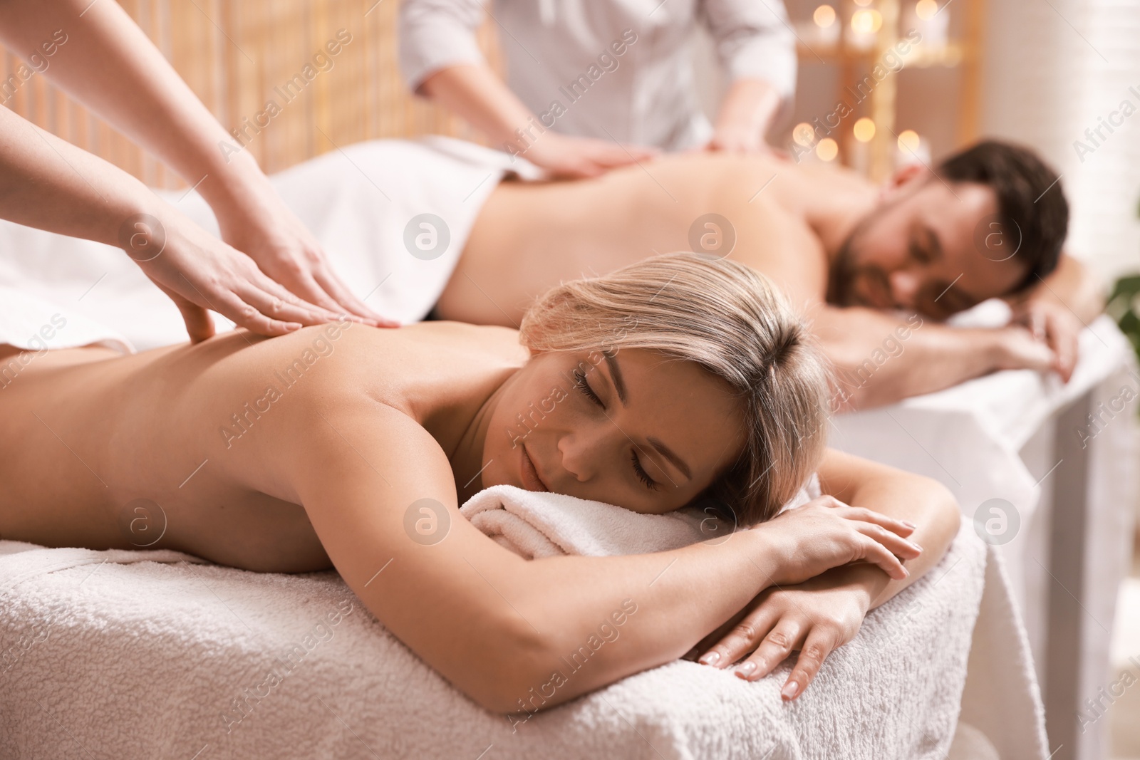 Photo of Couple receiving relaxing massage in spa salon, selective focus