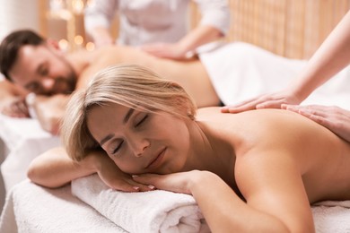 Photo of Couple receiving relaxing massage in spa salon, selective focus