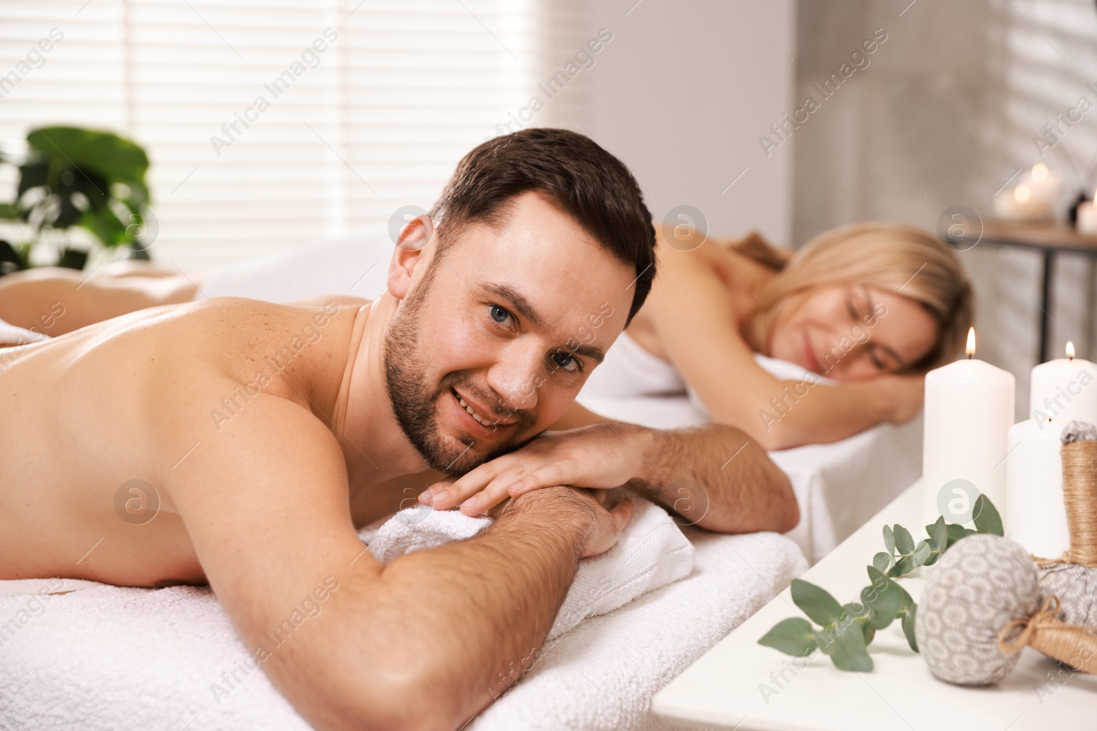 Photo of Happy couple lying on massage tables in spa salon, selective focus