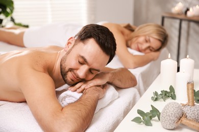 Couple lying on massage tables in spa salon, selective focus