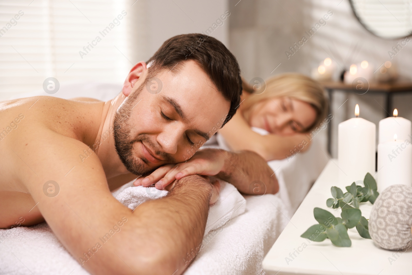 Photo of Couple lying on massage tables in spa salon, selective focus