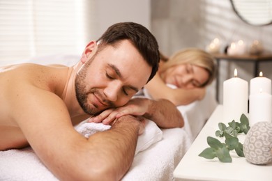 Couple lying on massage tables in spa salon, selective focus