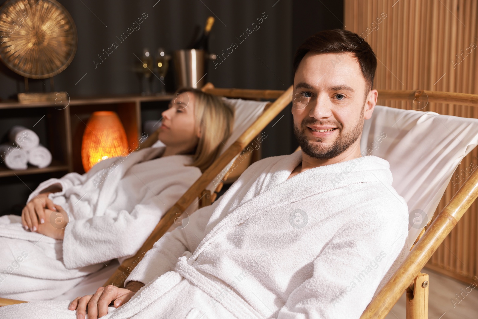 Photo of Happy couple in bathrobes relaxing in spa salon, selective focus