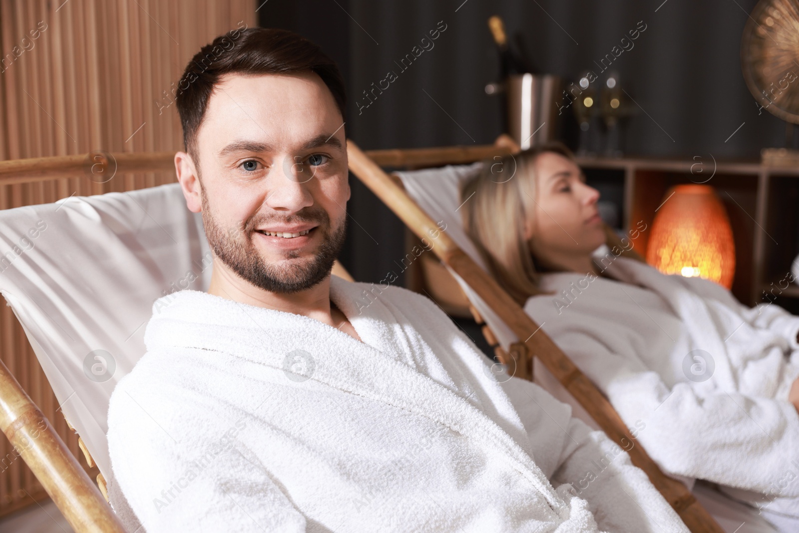 Photo of Happy couple in bathrobes relaxing in spa salon, selective focus