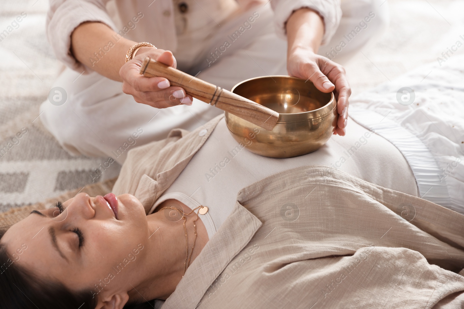 Photo of Woman undergoing singing bowl therapy lying on floor indoors