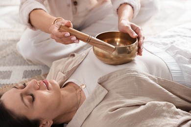 Woman undergoing singing bowl therapy lying on floor indoors