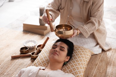 Woman undergoing singing bowl therapy lying on floor indoors