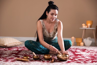 Woman with singing bowls and burning candles indoors