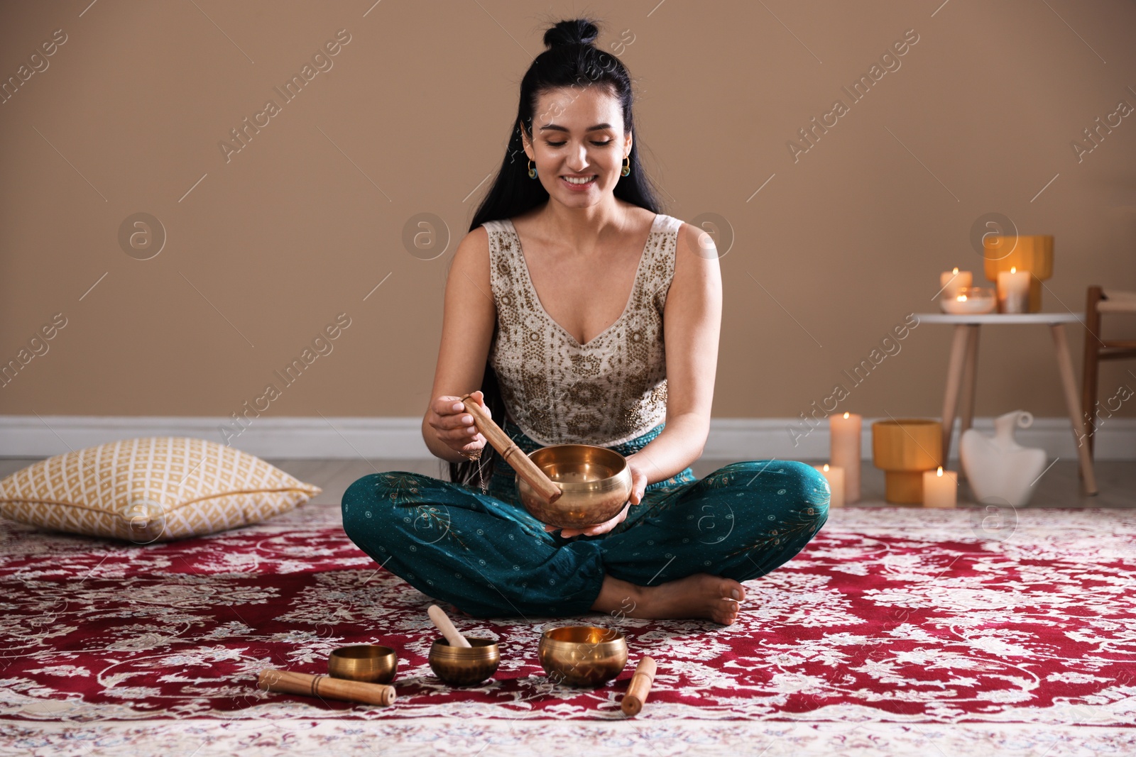 Photo of Woman with singing bowls and burning candles indoors