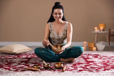 Woman with singing bowls and burning candles indoors