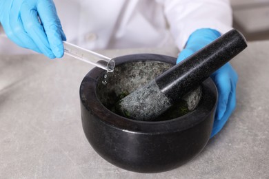 Photo of Biochemistry. Scientist with mortar and pestle working at grey table, closeup