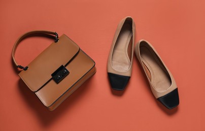 Photo of Pair of stylish shoes and bag on red-brown background, flat lay