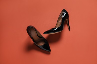 Photo of Pair of high heeled shoes on red-brown background, flat lay