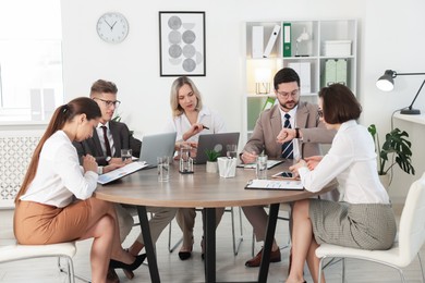 Photo of Coworkers working together at wooden table in office