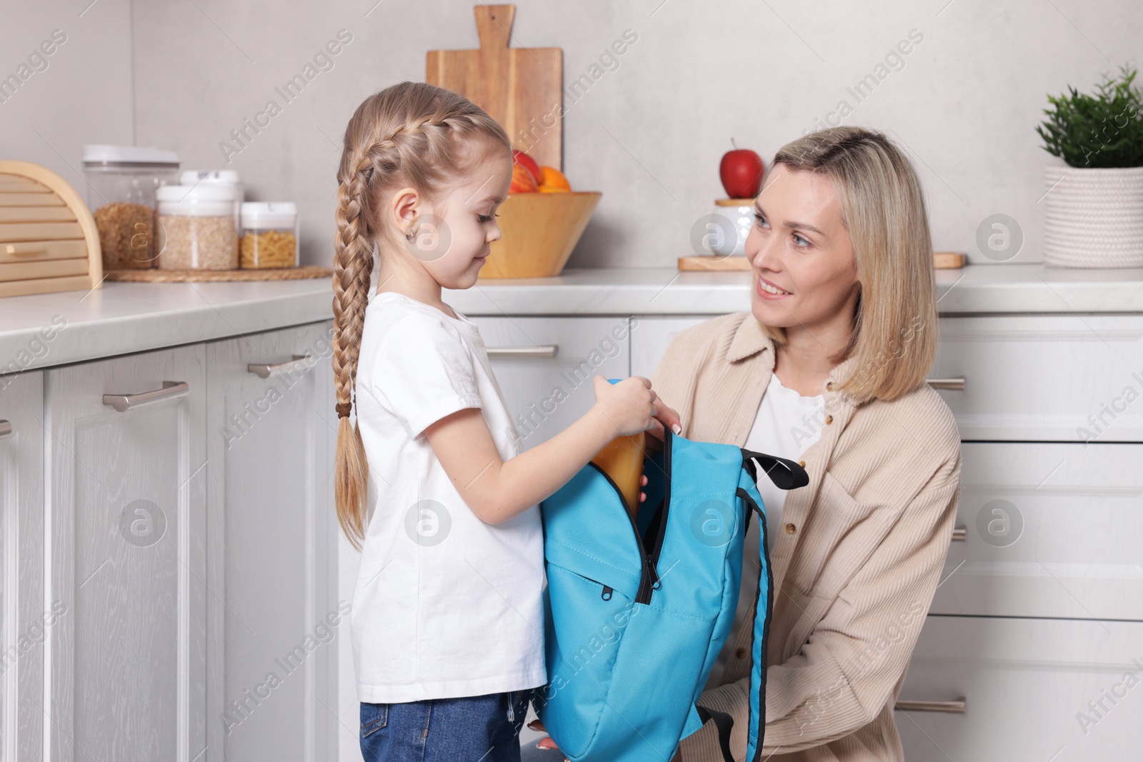 Photo of Mother packing her daughter's lunch in kitchen