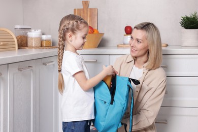 Mother packing her daughter's lunch in kitchen