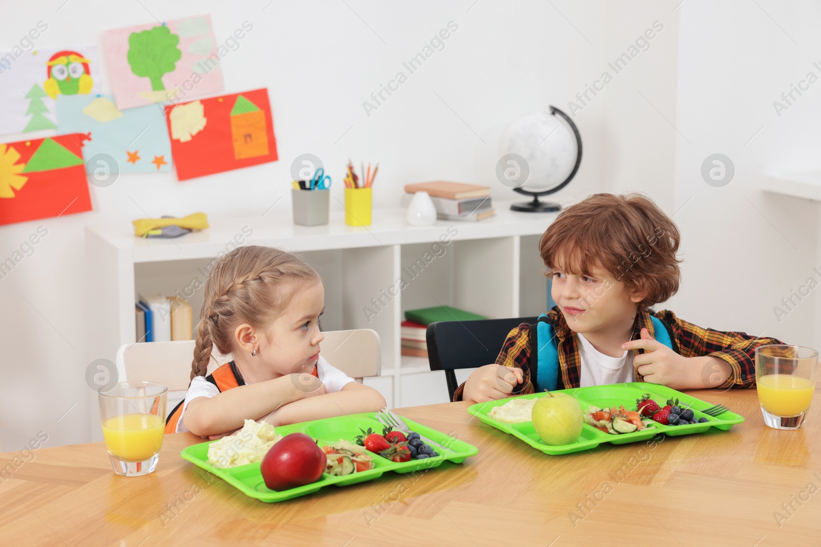 Photo of Cute little children eating lunch at wooden table in school