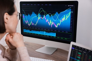 Stock exchange. Woman analysing financial market on computer at wooden table indoors