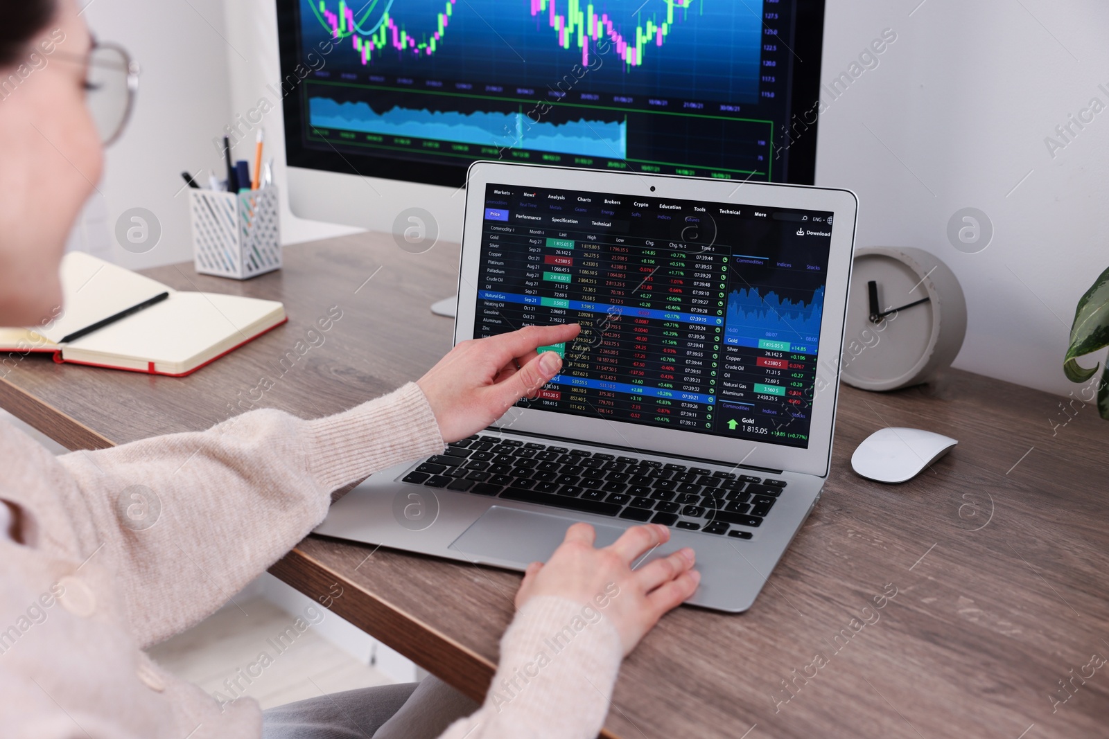 Photo of Stock exchange. Woman analysing financial market on laptop at wooden table indoors, closeup