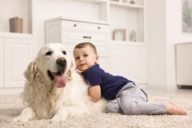 Photo of Little boy with cute dog on carpet at home