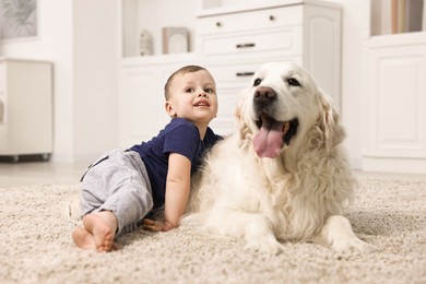 Photo of Happy little boy with cute dog on carpet at home