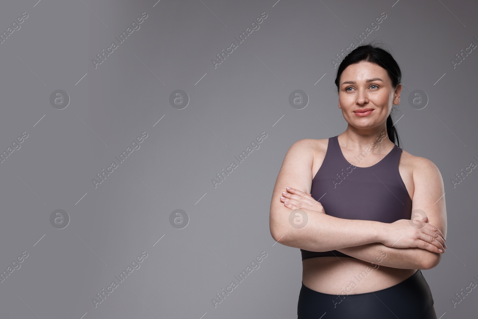 Photo of Plus size woman in gym clothes on grey background, space for text