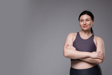 Plus size woman in gym clothes on grey background, space for text