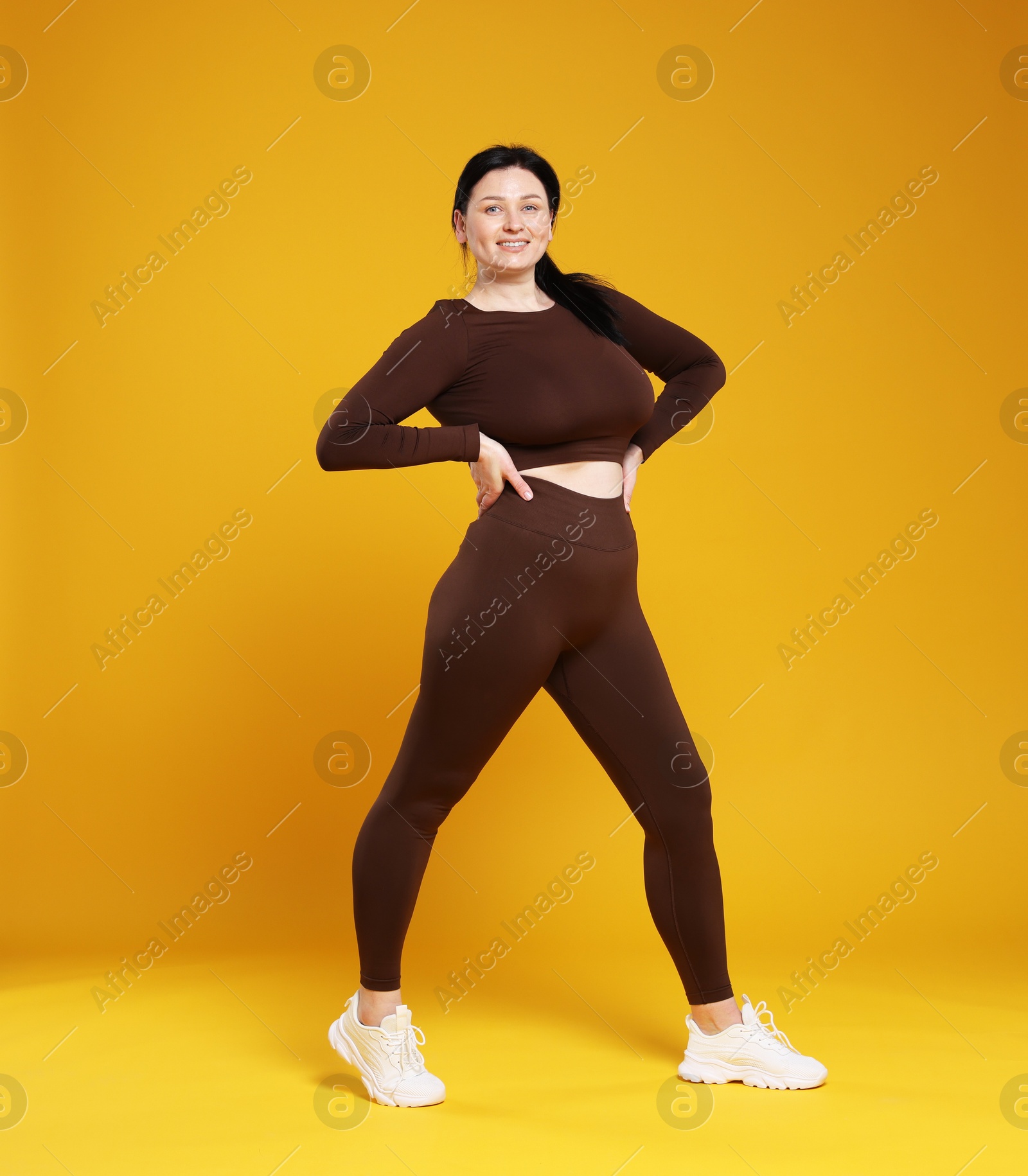 Photo of Plus size woman in gym clothes on orange background