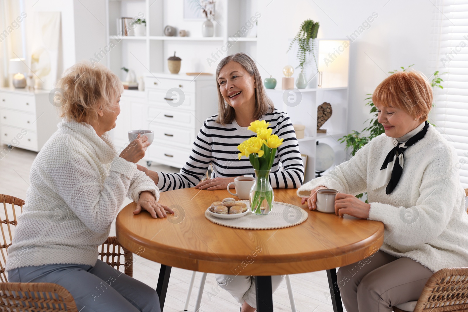 Photo of Friendship. Senior women enjoying hot drinks at table indoors