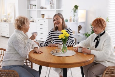 Photo of Friendship. Senior women enjoying hot drinks at table indoors