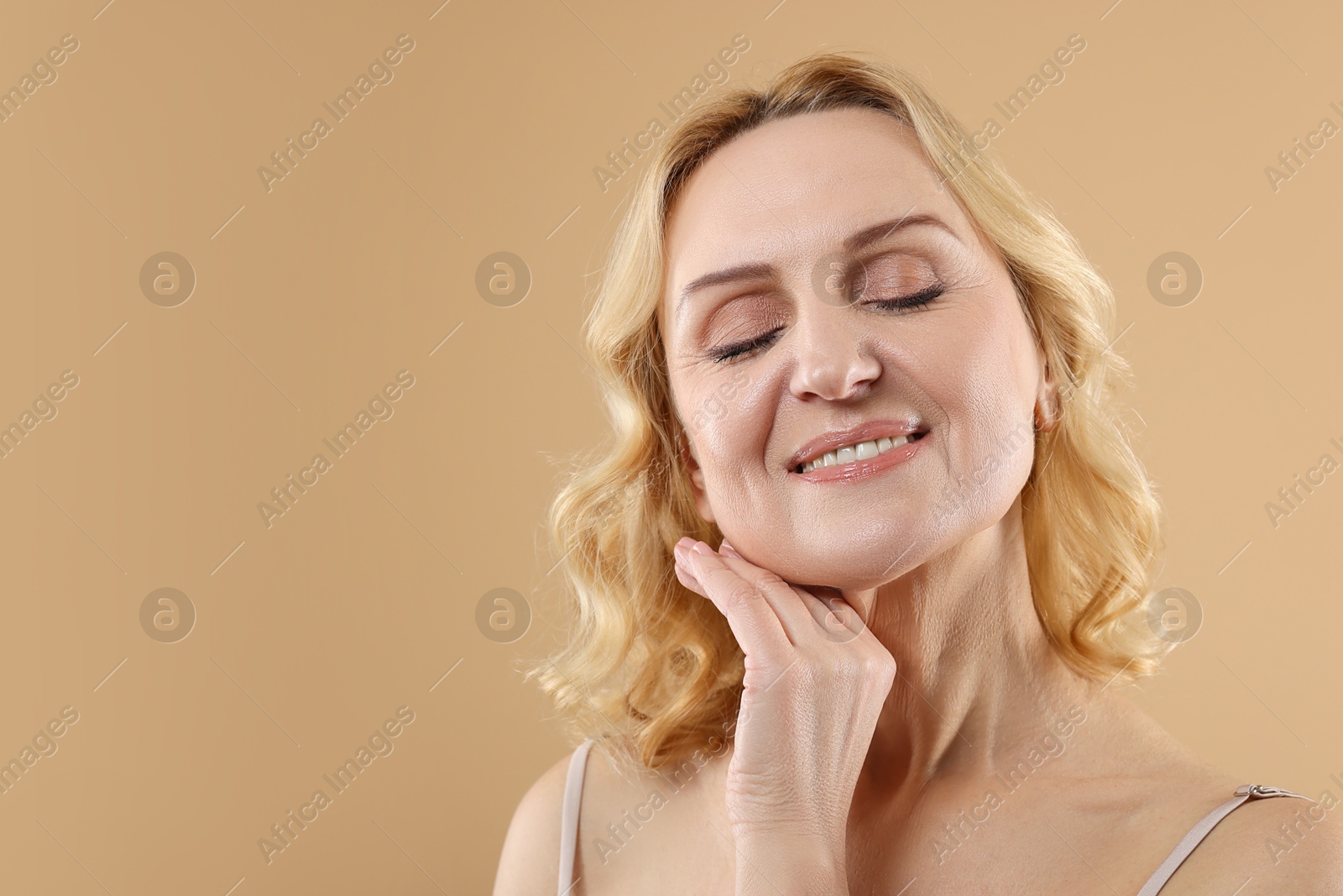 Photo of Smiling middle aged woman on beige background. Space for text