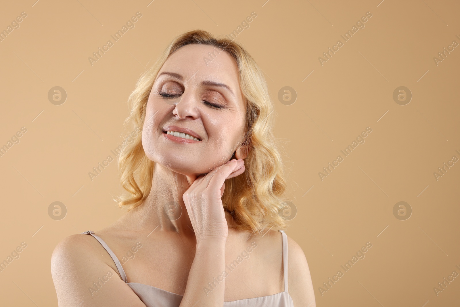 Photo of Smiling middle aged woman on beige background. Space for text