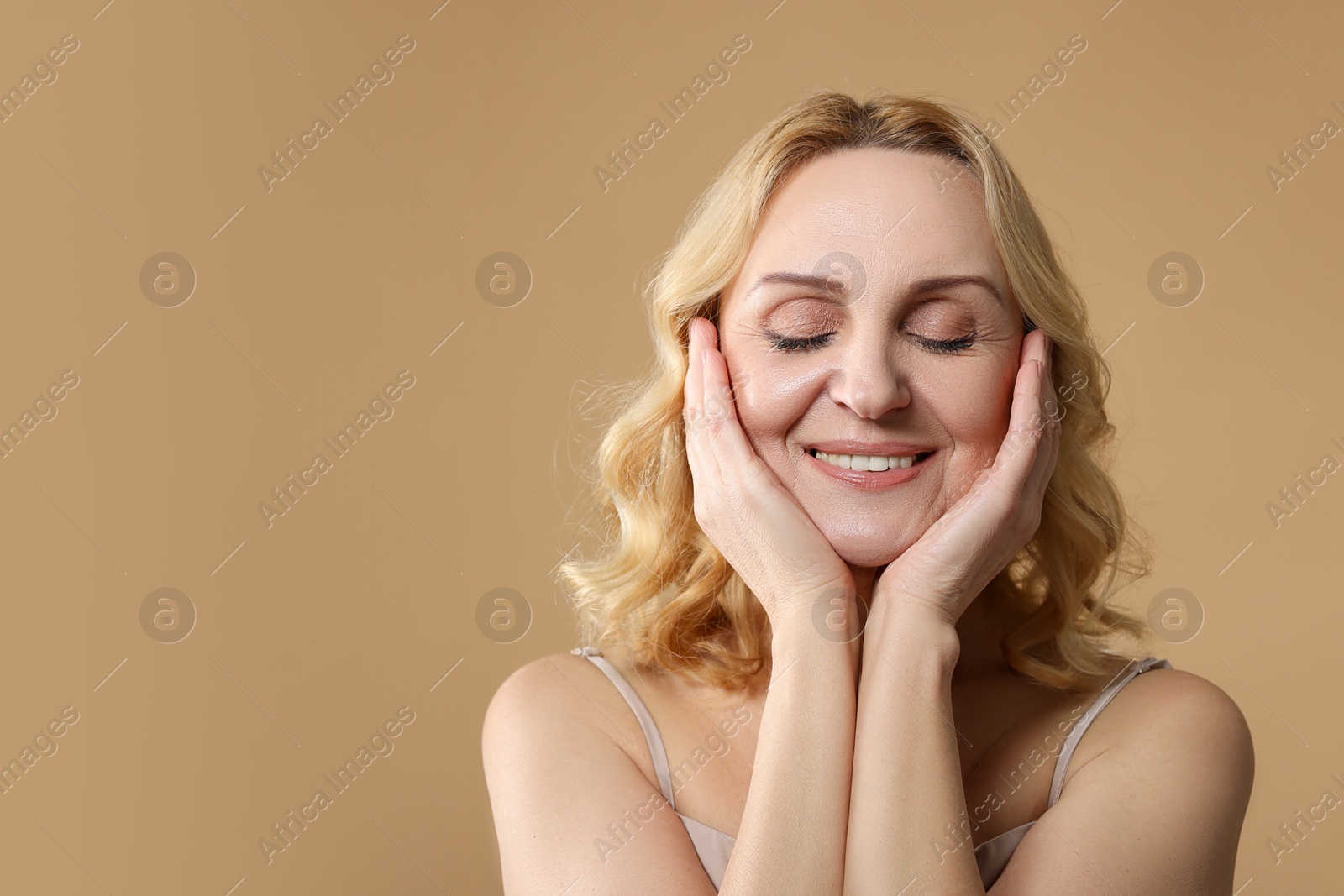 Photo of Smiling middle aged woman on beige background. Space for text