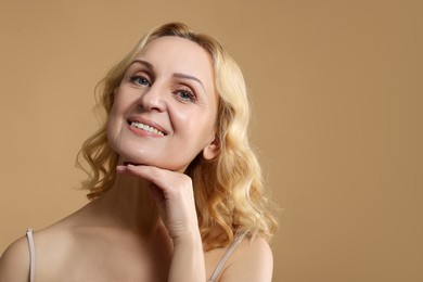 Photo of Portrait of smiling middle aged woman on beige background. Space for text