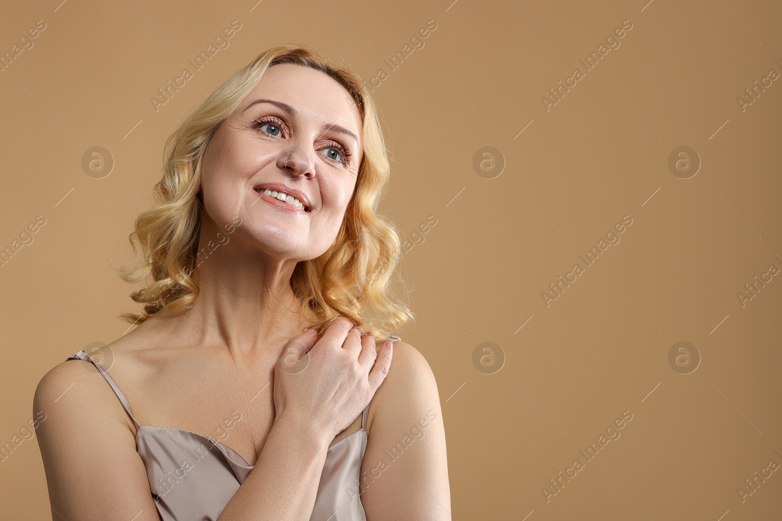 Photo of Smiling middle aged woman on beige background. Space for text