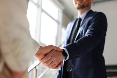 Photo of Men shaking hands in agreement indoors, closeup