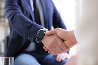 Photo of Men shaking hands during meeting indoors, closeup