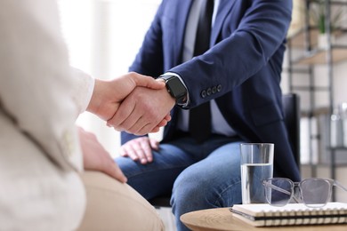 Photo of Men shaking hands during meeting indoors, closeup