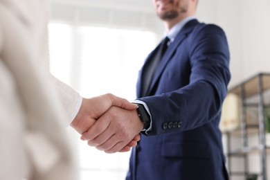 Men shaking hands during meeting indoors, closeup