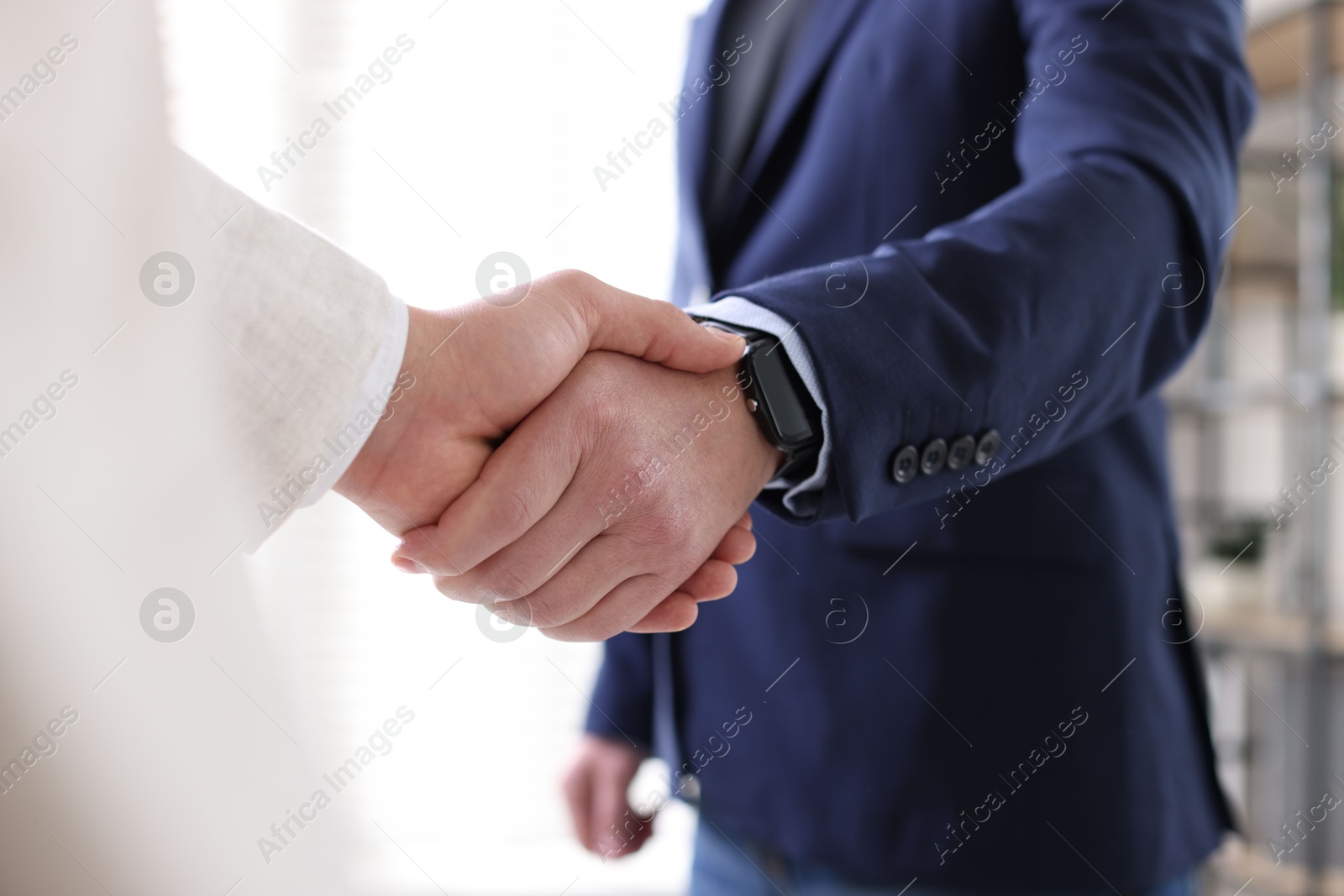 Photo of Men shaking hands during meeting indoors, closeup